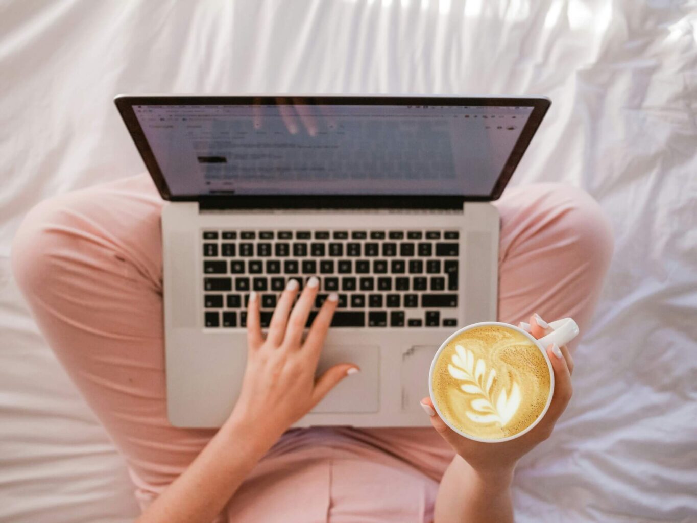 Woman Crossed Legged On Bed Working On Laptop With Coffee In Hand - Best Online Business Tools 