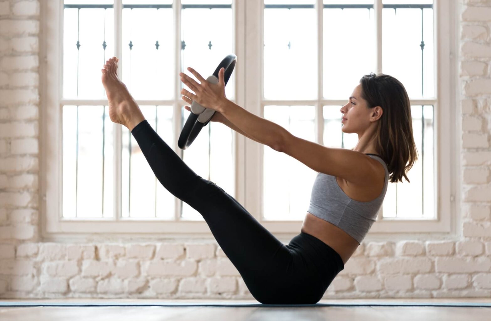 Woman Practicing Pilates on Mat With Pilates Ring