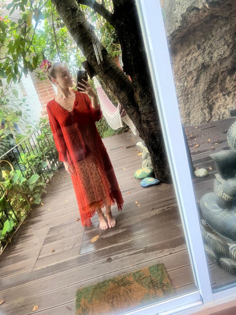 Jennifer Read-Dominguez reviews women's retreat in Andalusian mountains - in flowing burnet orange dress barefoot outside a cave room at Molino del Rey wellness retreat