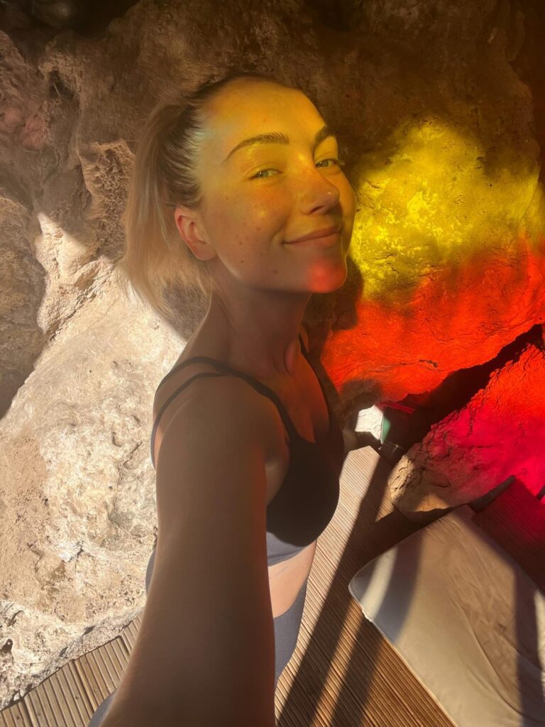 Jennifer Read-Dominguez - The Women's Journal founder smiling in natural cave light at a yoga retreat bathed in rainbow reflections at Molino del Rey yoga retreat in Andalusia