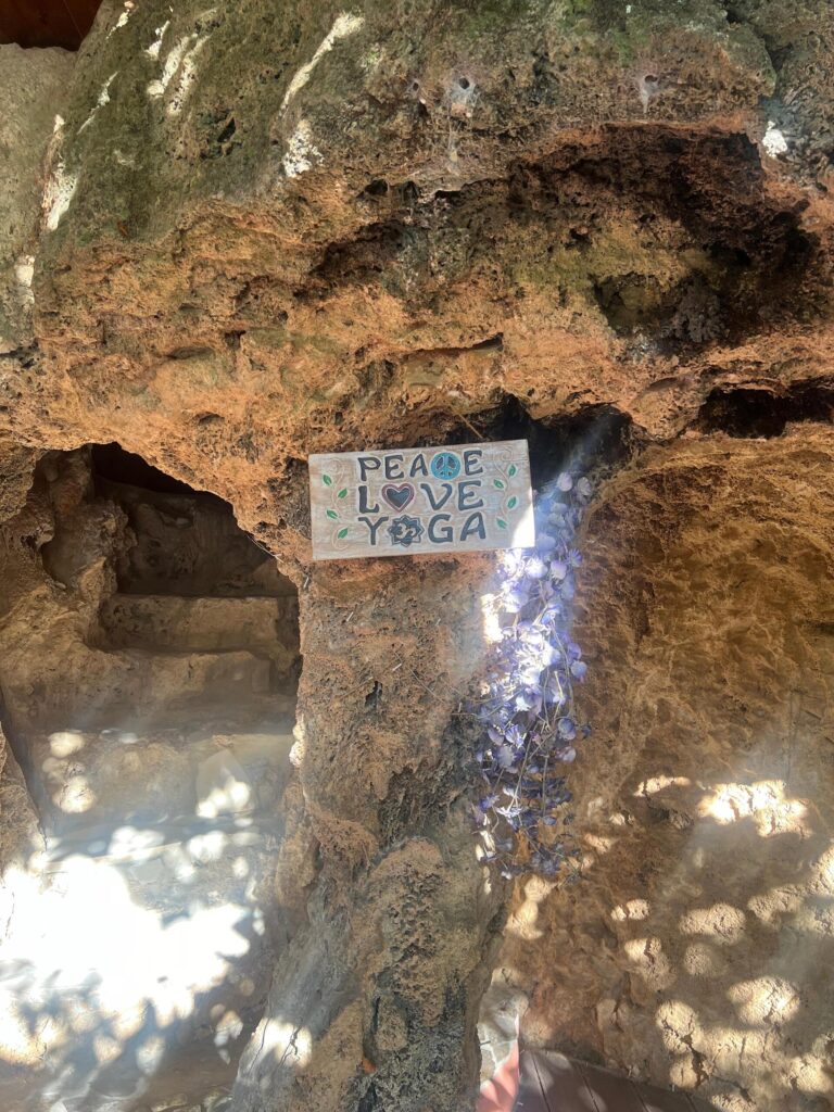 Hand-painted 'Peace Love Yoga' sign in natural sunlight nestled in natural rock and caves at Molino del Rey yoga retreat in Andalusia