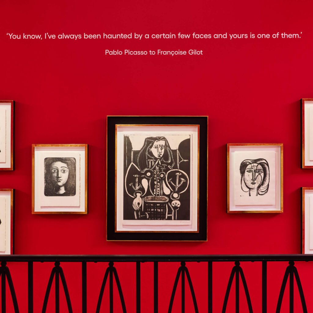Wall display of Picasso’s portraits of Françoise Gilot against red walls at Picasso: A Legacy, the new free Picasso exhibition in London.