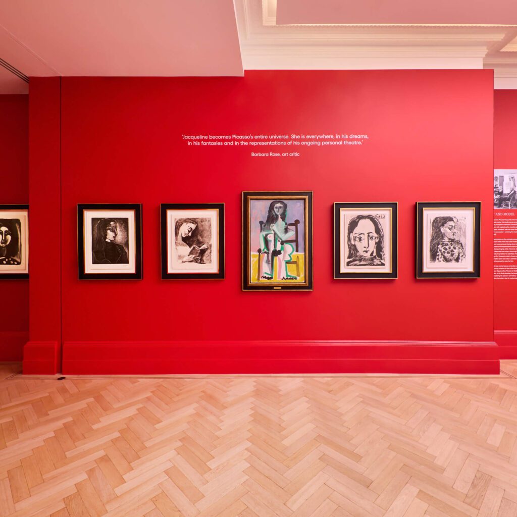 Picasso: A Legacy Exhibition showing portraits of Jacqueline Roque on bold red walls at the new free Picasso exhibition in London - Halcyon Gallery Bond Street